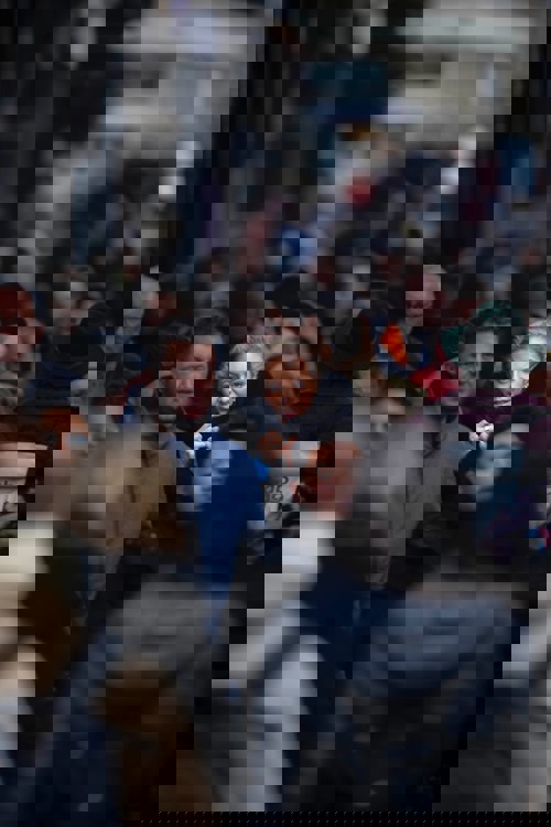 Focused view on a woman in a crowded street looking directly at the camera with a slight smile, surrounded by various other pedestrians in soft focus.